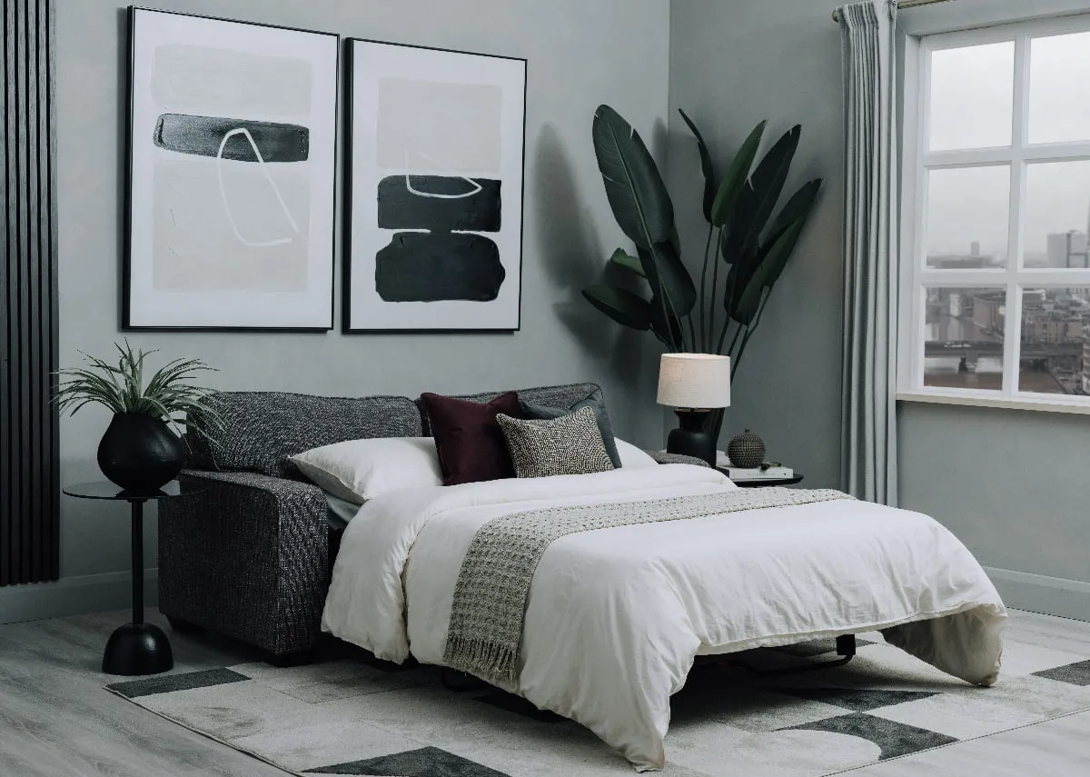 A lifestyle image of the Nevada bed made up with duvet and plants in a living space.