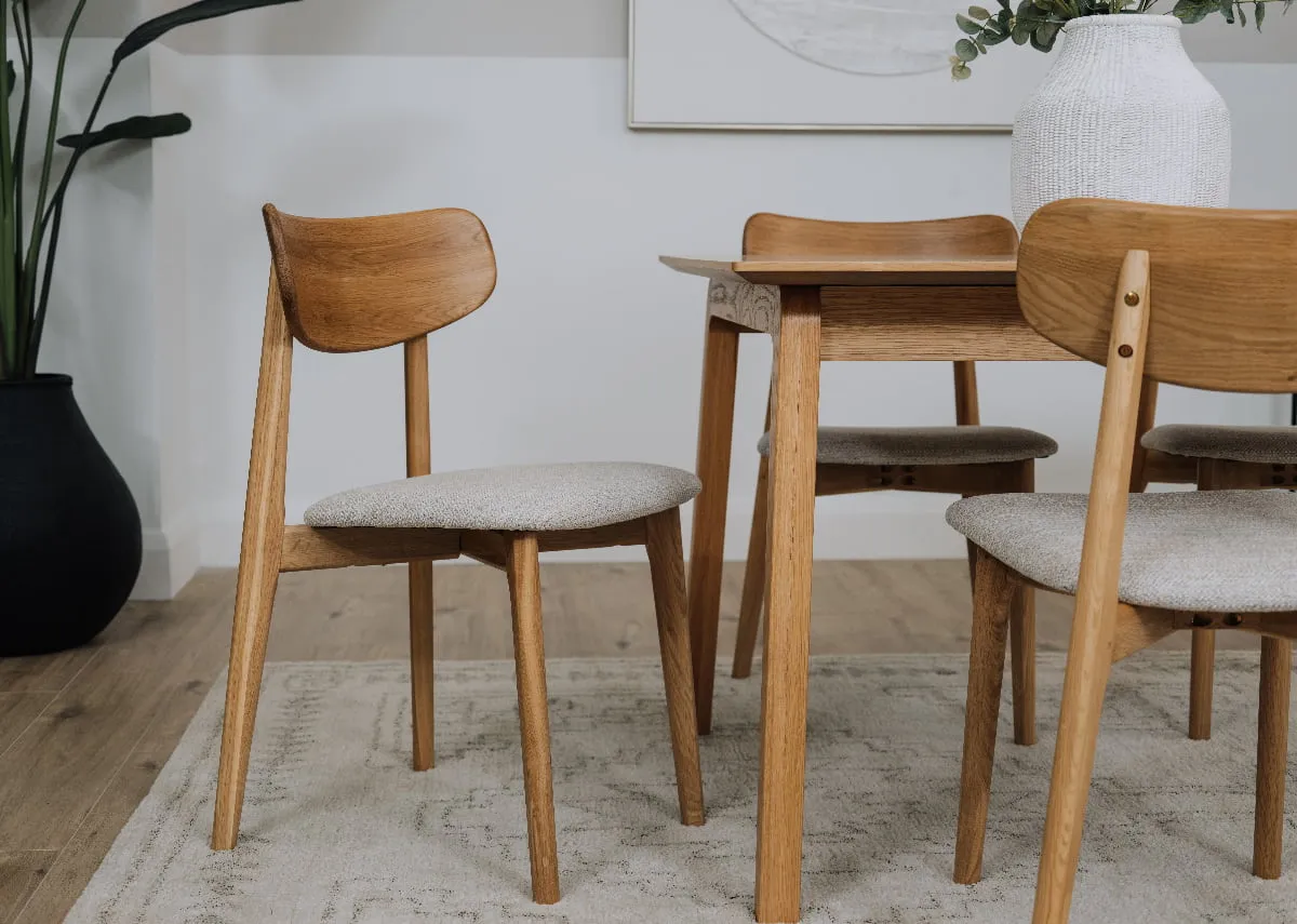 A lifestyle image of the Baro oak dining chair with fabric seat paired with the matching oak dining table.