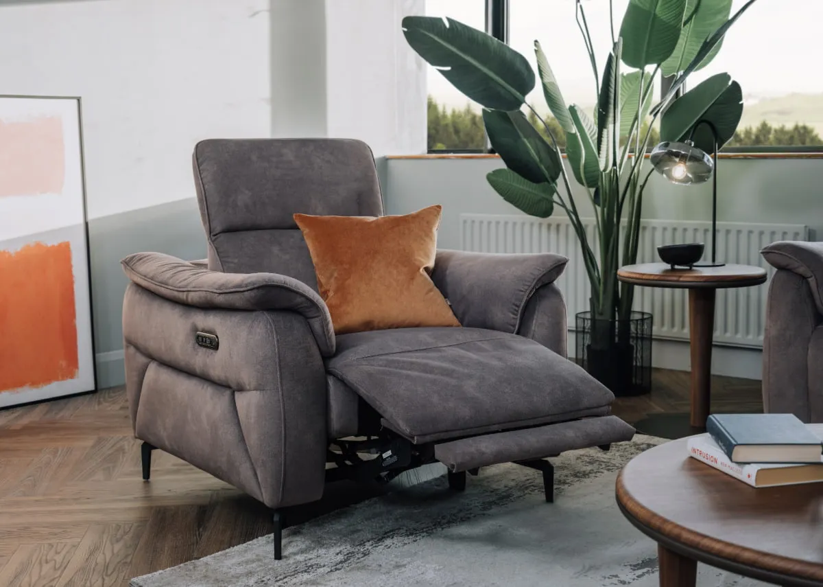 A lifestyle image of the Carlton recliner with recliner out and headrest up with gold cushion and echo coffee table