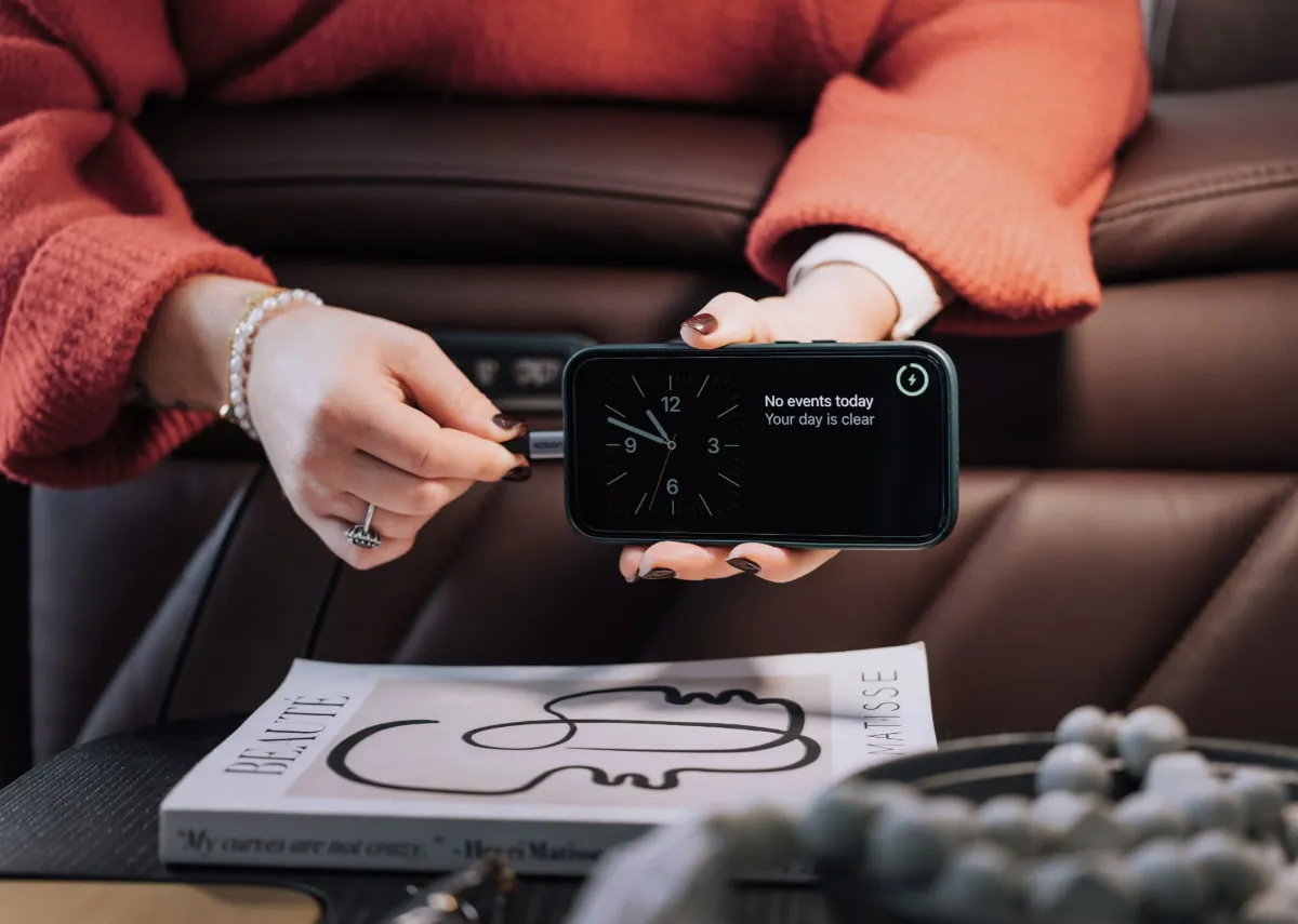 A closeup lifetsyle image of Ola charging a phone using the USB charger to the side of the armrest