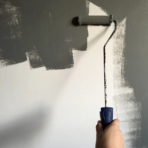 Paint roller painting wall in grey paint.