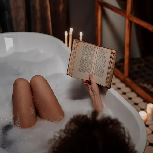 Woman in bubble bath with book.