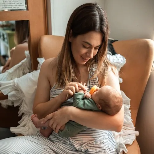 Woman nursing baby in chair.