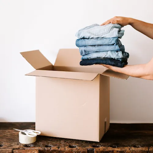 Clothes being put into cardboard box.