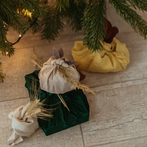Gifts wrapped in cloth under the Christmas tree.