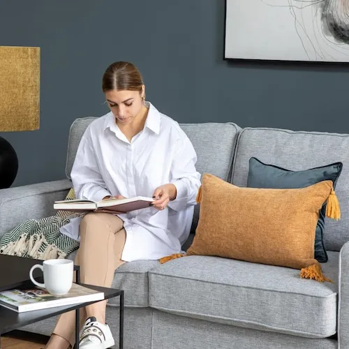 EZ Living Furniture's social media Ola sits on grey sofa.
